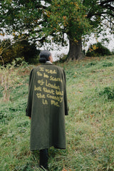 Person standing in a field with a text-covered coat