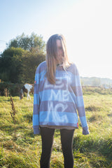 Person wearing a striped sweater with text in an outdoor setting