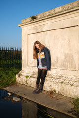 Woman standing by a stone wall with a clear blue sky