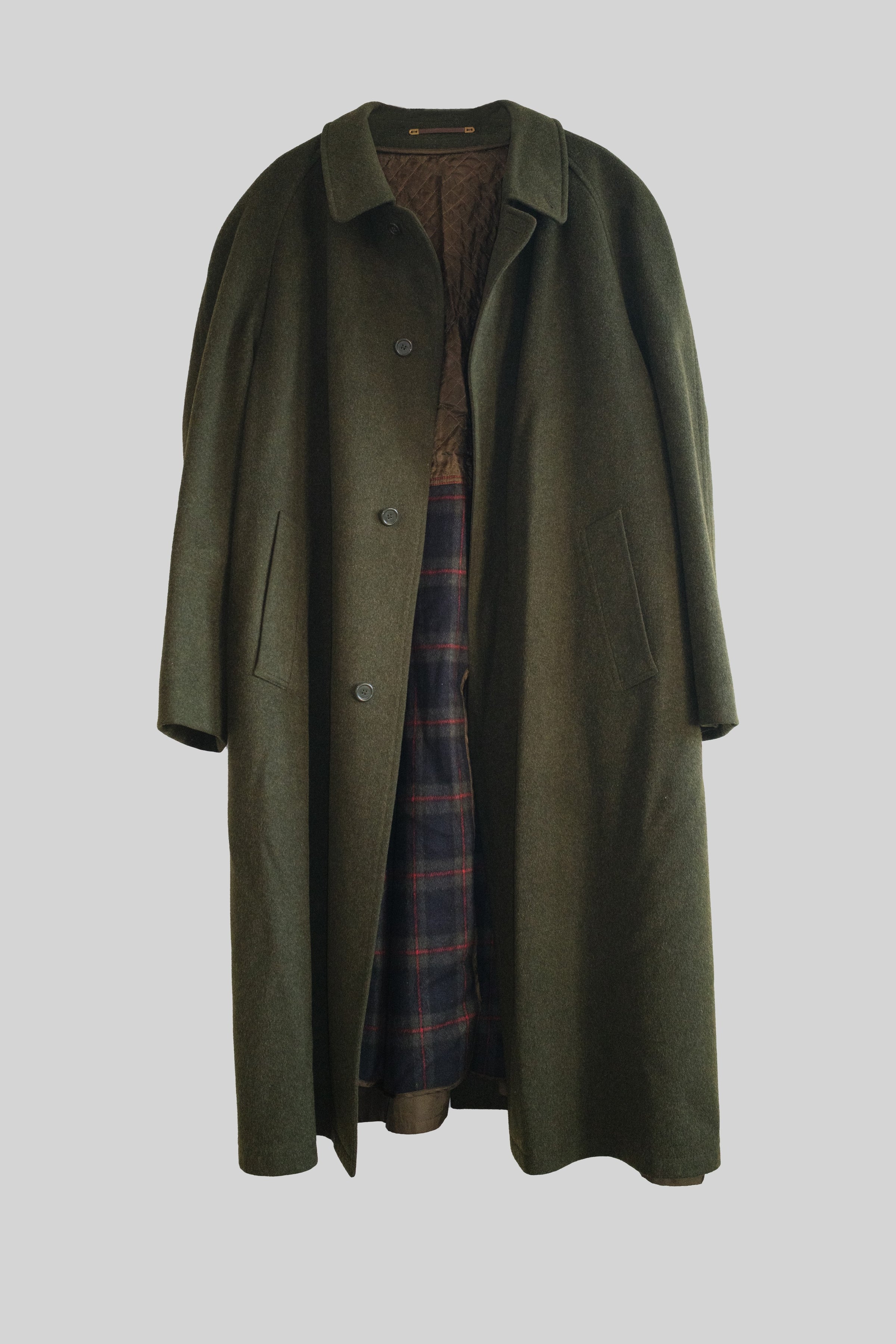 Green overcoat with plaid lining on a light gray background